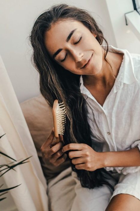 Young woman applying natural organic essential oil on hair and skin. Home spa and beauty rituals. Skin care.